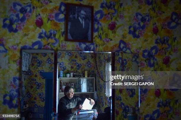 An elderly woman casts her ballot at her house during Russia's presidential election in the village of Khrapovo, some 55 km north of Smolensk, on...