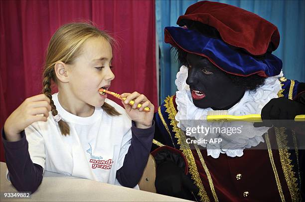 Man dressed as Black Petes helps a child in a primary school practice brushing her teeth as part of a project which teaches children how to properly...