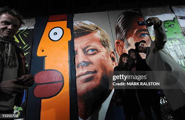 People stand on November 9, 2009 in front an original, 10-panel section of the Berlin Wall at an event to commemorate the 20th anniversary of the...