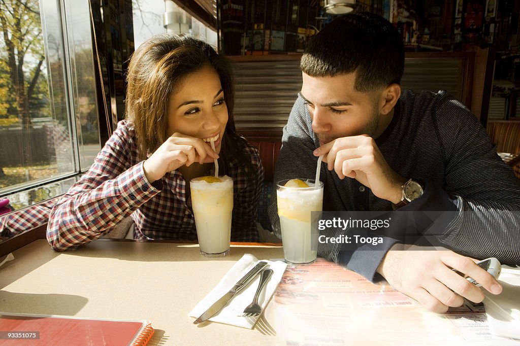 Young adult couple drinking lemonade at diner