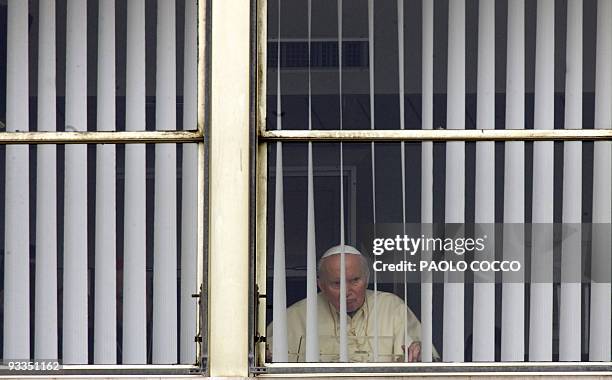 Pope John Paul II peers out behind the window of Rome's Gemelli hospital 13 March 2005, during his traditional Sunday Angelus prayer. The 84-year-old...