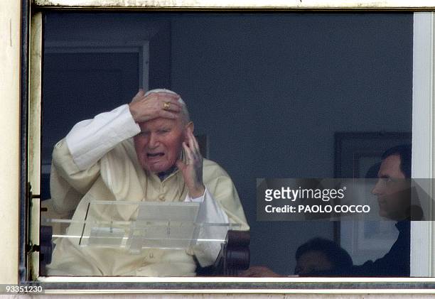 Pope John Paul II holds his face as he appears behind the window of Rome's Gemelli hospital 13 March 2005, during his traditional Sunday Angelus...