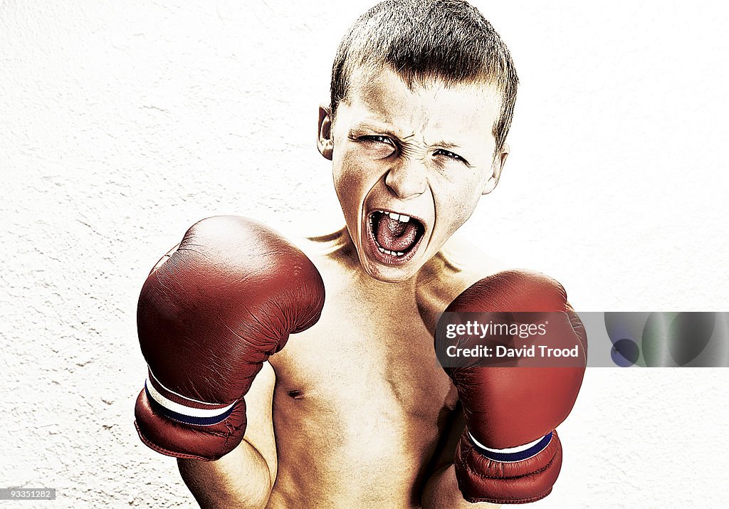 Young boy with boxing gloves yelling at camera.