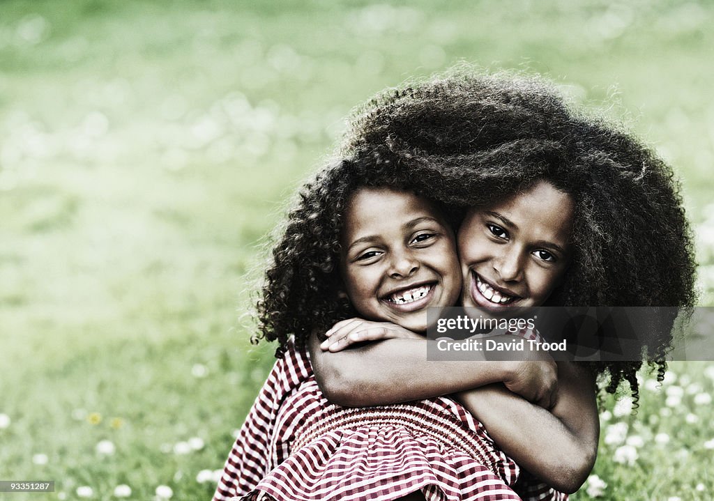Sisters hugging on the grass