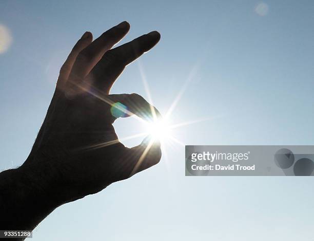 holding the sun in the fingers. - david trood photos et images de collection