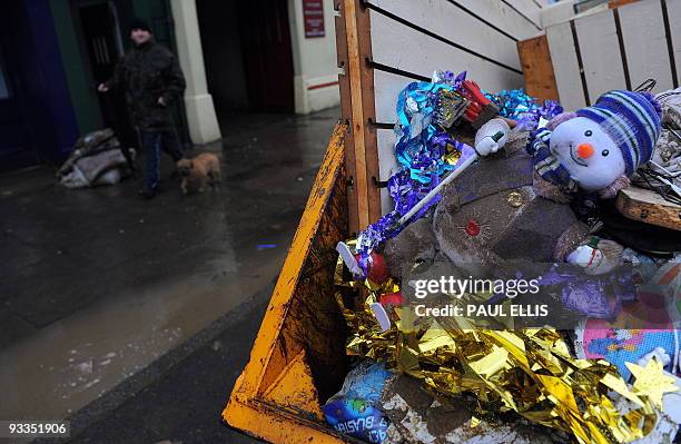 Man walks past a skip containing damaged Christmas decorations in Cockermouth, north-west England on November 24, 2009. Heavy rain returned to...