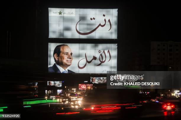 Long exposure picture taken on late night of March 17 shows a giant election campaign board supporting Egyptian President Abdel Fattah al-Sisi in the...