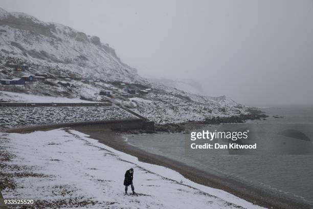 Man walks on a snow covered Chesil Beach on the Island of Portland during a weather front that has been dubbed the 'mini beast from the East' on...