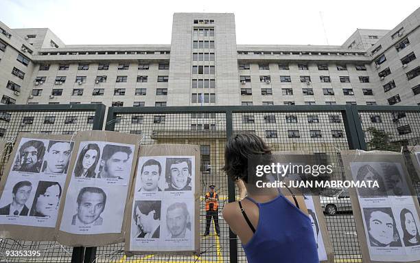 Member of the H.I.J.O.S. Human rights organization, hangs pictures of disappeared people, in front of the court in Buenos Aires on November 24 where...