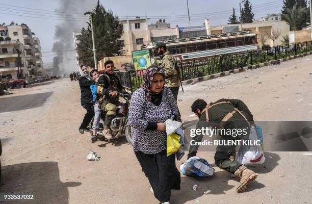 Turkish-backed Syrian rebels help evacuate a wounded woman following explosions in the city of Afrin in northern Syria on March 18 after Turkish...