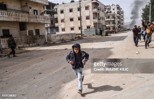 Civilians run for cover from explosions in the city of Afrin in northern Syria on March 18 after Turkish forces and their rebel allies took control...