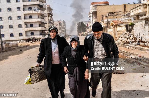 Civilians run for cover from explosions in the city of Afrin in northern Syria on March 18 after Turkish forces and their rebel allies took control...