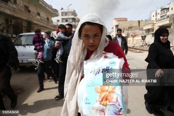 Civilians run for cover from explosions in the city of Afrin in northern Syria on March 18 after Turkish forces and their rebel allies took control...