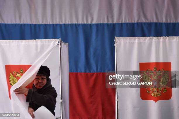 Woman walks out of a voting booth at a polling station during Russia's presidential election in the village of Novye Bateki, some 15 km north of...