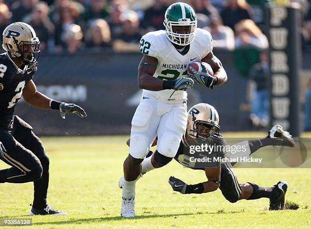 Larry Caper of the Michigan State Spartans runs the ball as David Pender of the Purdue Boilermakers tries to tackle from behind at Ross-Ade Stadium...