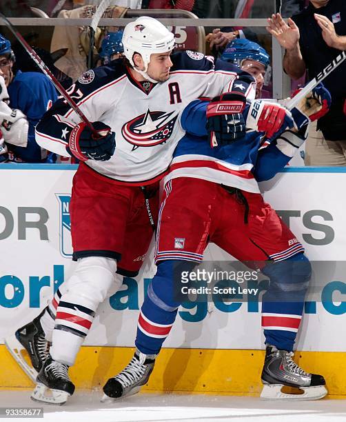 Christopher Higgins of the New York Rangers is checked along the boards by Rostislav Klesla of the Columbus Blue Jackets on November 23, 2009 at...