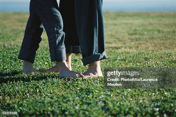 young couple standing barefoot in field, low section - playing footsie stock pictures, royalty-free photos & images