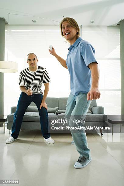 two men playing video games with wireless controllers - palanca de juego fotografías e imágenes de stock