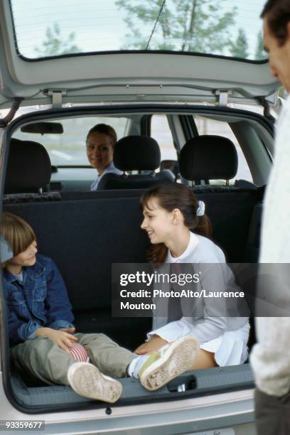 siblings sitting in back of station wagon, parents watching - station wagon stock pictures, royalty-free photos & images