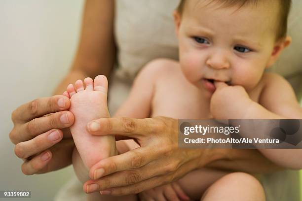 mother holding baby on lap, playing with baby's foot, cropped - feet sucking stock pictures, royalty-free photos & images