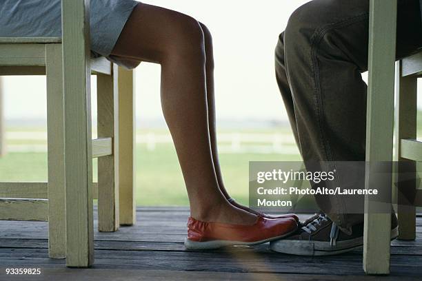 young couple seated at table facing one another, woman's feet touching mans, low section - playing footsie stock pictures, royalty-free photos & images