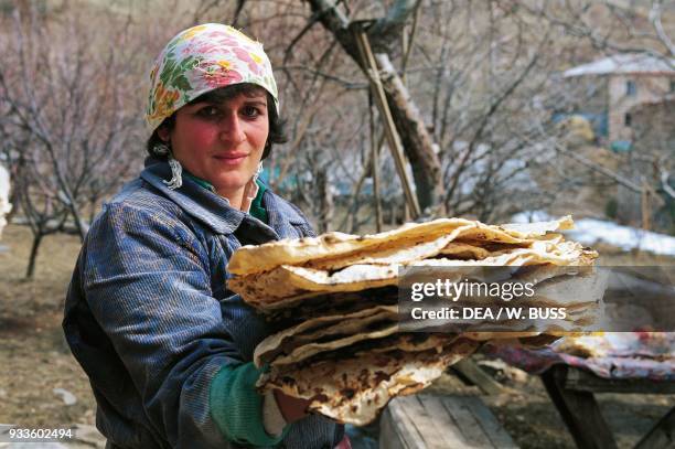 Woman holding up a stack of traditional Armenian bread , Bjni, Armenia.