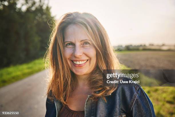 portrait of smiling woman in the countryside - middle age woman stock-fotos und bilder