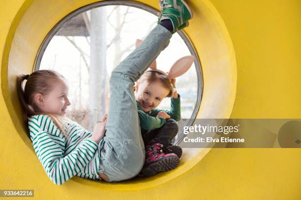 two happy children sitting on the frame of a circular window in a yellow wall - family picture frame stockfoto's en -beelden