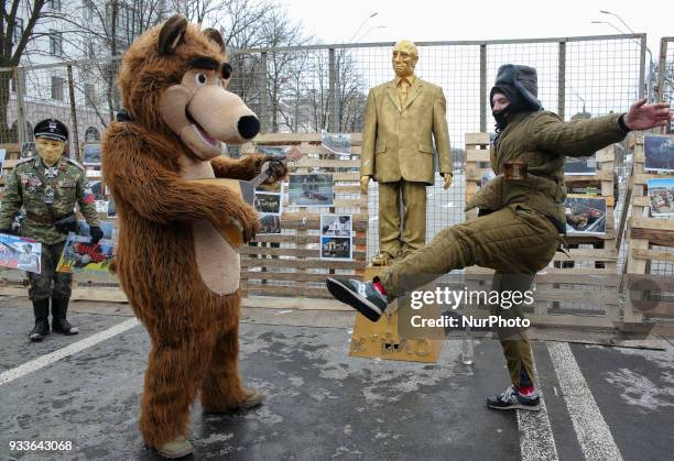 Activists one dressed in a bear with balalaika costume and another - in a soviet army winter cotton-padded jacket dance around a monument of 'A...