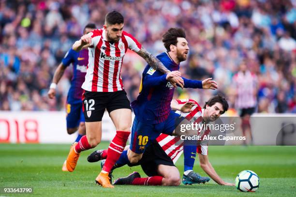 Lionel Messi of FC Barcelona is brought down by Unai Nunez and Mikel San Jose of Athletic Club during the La Liga match between Barcelona and...