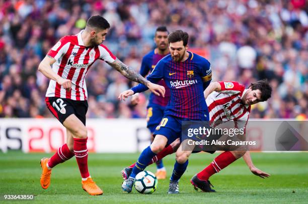 Lionel Messi of FC Barcelona is brought down by Unai Nunez and Mikel San Jose of Athletic Club during the La Liga match between Barcelona and...