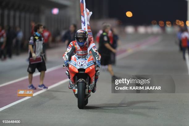 Ducati Team's Italian rider Andrea Dovizioso rides his Ducati and holds a flag after winning the 2018 Qatar Moto GP Grand Prix at the Losail...