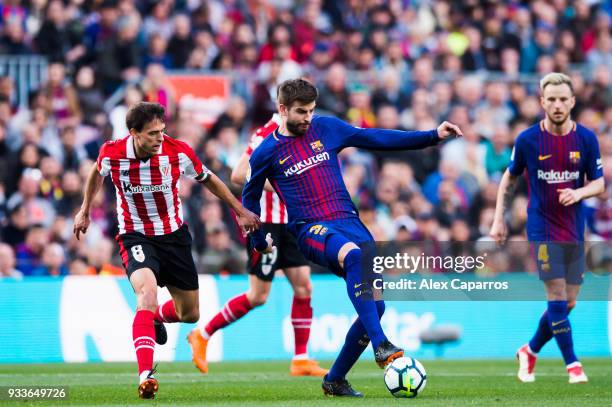 Gerard Pique of FC Barcelona conducts the ball under pressure from Ander Iturraspe of Athletic Club during the La Liga match between Barcelona and...