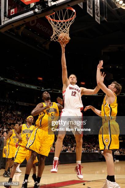 Rasho Nesterovic of the Toronto Raptors puts up the shot in the paint against Roy Hibbert and Troy Murphy of the Indiana Pacers during a game on...