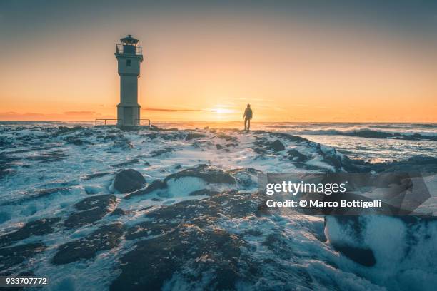 tourist admiring sunset at akranes lighthouse, vesturland, iceland. - akranes bildbanksfoton och bilder