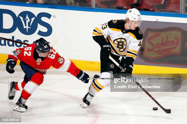 Danton Heinen of the Boston Bruins skates with the puck against Denis Malgin of the Florida Panthers at the BB&T Center on March 15, 2018 in Sunrise,...