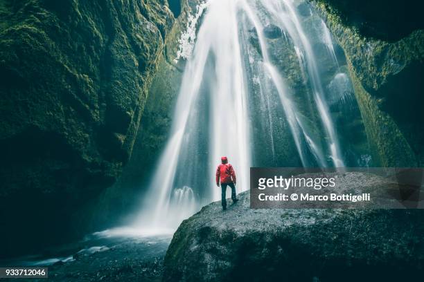 tourist on a rock admiring gljufrabui waterfall, iceland - awe stockfoto's en -beelden