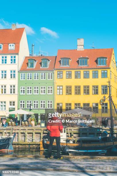 tourist admiring the nyhavn waterfront, copenhagen. - oresund region photos et images de collection