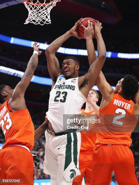 Xavier Tillman of the Michigan State Spartans battles for the ball with Frank Howard and Matthew Moyer of the Syracuse Orange during the first half...