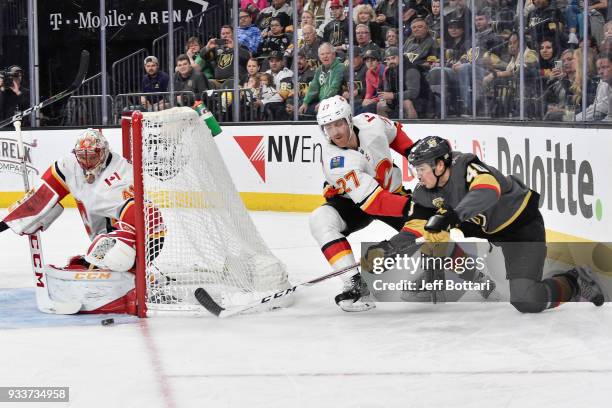 Ryan Carpenter of the Vegas Golden Knights skates with the puck while Dougie Hamilton and Mike Smith of the Calgary Flames defends during the game at...