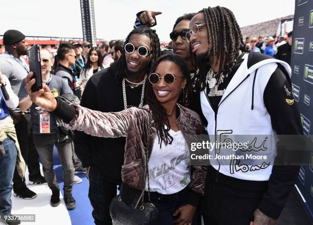 Actress Shanola Hampton poses for a photo with Migos during the Monster Energy NASCAR Cup Series Auto Club 400 at Auto Club Speedway on March 18,...
