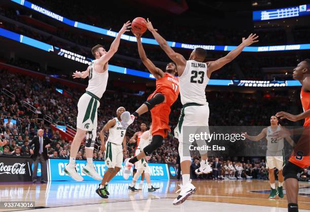 Oshae Brissett of the Syracuse Orange drives to the basket against Ben Carter and Xavier Tillman of the Michigan State Spartans during the second...