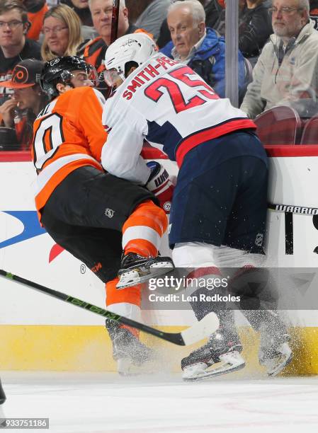 Jordan Weal of the Philadelphia Flyers is checked along the boards by Devante Smith-Pelly of the Washington Capitals on March 18, 2018 at the Wells...