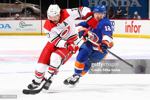 Justin Faulk of the Carolina Hurricanes carries the puck in the offensive zone amid pressure from Josh Bailey of the New York Islanders during the...