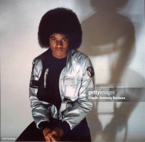 Portrait of American Pop and R&B musician Michael Jackson , dressed in a shiny silver jacket, as he poses with his arms crossed, November 1977.