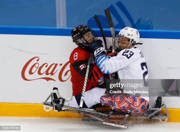 Tyler McGregor of Canada battles for the puck with Rico Roman of the United States in the Ice Hockey gold medal game between United States and Canada...