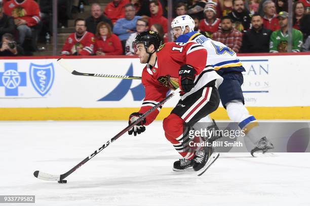 Alex DeBrincat of the Chicago Blackhawks controls the puck next to Carl Gunnarsson of the St. Louis Blues in the second period at the United Center...