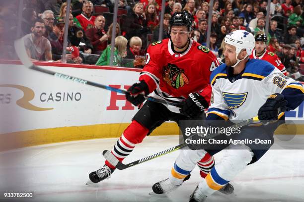 John Hayden of the Chicago Blackhawks and Kyle Brodziak of the St. Louis Blues skate around the boards in the second period at the United Center on...