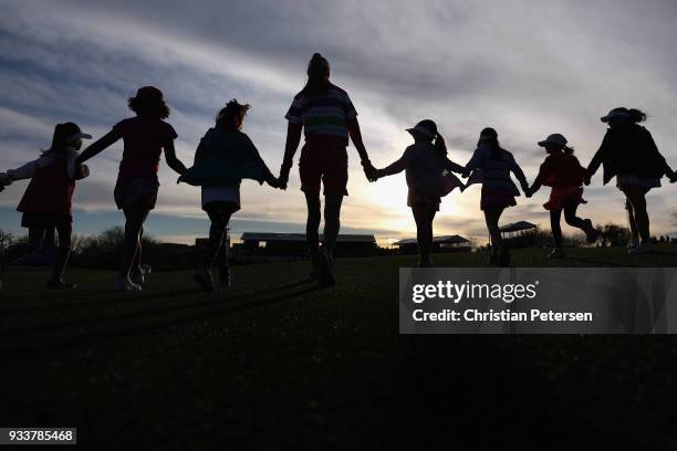 Members of 'Girls Golf' hold hands as they walk the 18th fairway behind the leaders during the final round of the Bank Of Hope Founders Cup at...