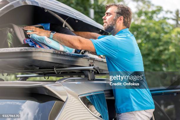 men filling cargo box container on roof rack for vacations or camping - car camping luggage stock pictures, royalty-free photos & images